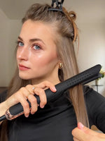 Woman using a hair straightener with a blurred background